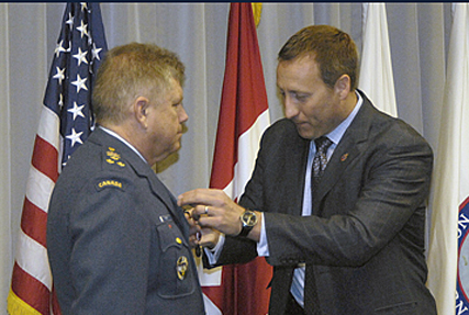 PETERSON AIR FORCE BASE, Colo. - Canadian Minister of National Defense Peter MacKay presents the Queen Elizabeth II Diamond Jubilee Medal to Raoyal Canadian Air Force Lt. Gen. Alain Parent, NORAD Deputy Commander, during his visit to headquarters NORAD & USNORTHCOM on Jan. 14. The medal was created to mark the 2012 celebrations of the 60th anniversary of Queen Elizabeth II's accession o the Throne as Queen of Canada.